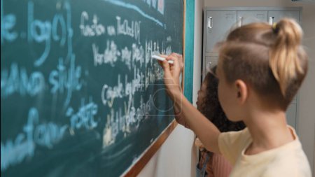 Photo for Diverse student studying coding engineering prompt while writing answer on blackboard. Intelligence children planning and learning about coding development plan. Successful boy sharing idea. Pedagogy. - Royalty Free Image