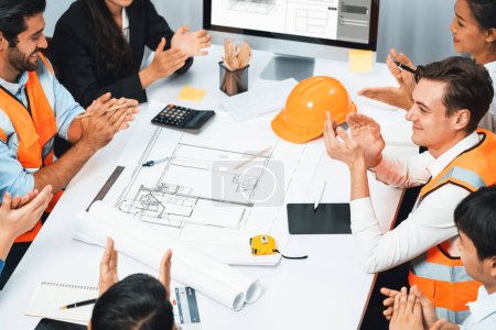 Photo for Diverse group of civil engineer and client feels excited and applauding after successful agreement on architectural project, review construction plan and building blueprint at meeting table.Prudent - Royalty Free Image