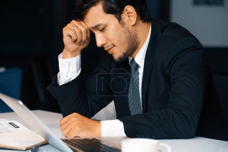 Foto de Joven infeliz, el hombre de negocios se siente estresado en la oficina debido a la crisis económica y la terrible pérdida de la compañía. Concepto de fracaso empresarial. BARROS - Imagen libre de derechos