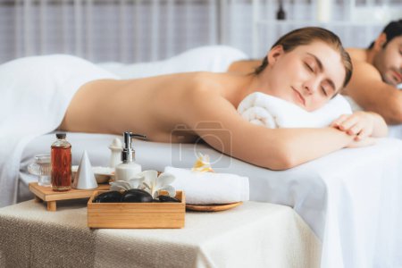 Téléchargez les photos : Massage aromathérapie à la lumière du jour ou configuration de salon de spa avec décor de mise au point et accessoires de spa sur femme floue profitant d'un massage aromatique spa dans un cadre de villégiature ou d'hôtel. Tranquillité - en image libre de droit