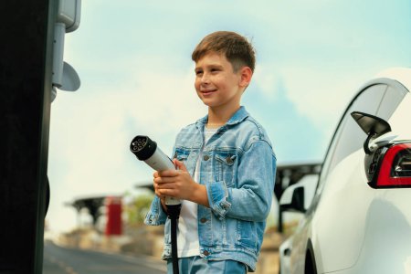 Photo for Little boy recharging eco-friendly electric car from EV charging station. EV car road trip travel concept for alternative transportation powered by clean renewable and sustainable energy. Perpetual - Royalty Free Image
