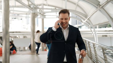 Photo for Smart caucasian businessman calling his colleague to plan financial strategy while walking to workplace. Front view of manager using mobile phone to communicate with marketing team. Lifestyle. Urbane. - Royalty Free Image