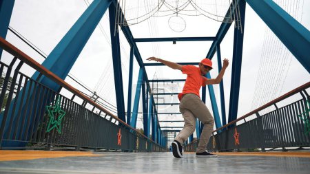 Photo for Skilled asian hipster perform footstep at bridge with low angle camera while wearing stylish cloth. Professional stress dancer practice break dancing. Modern lifestyle. Outdoor sport 2024. Sprightly. - Royalty Free Image