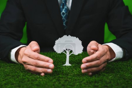 Businessman holding tree icon symbolize eco-friendly business corporation committed to environmental friendly CSR practice and zero carbon emission. Corporate responsible for greener society. Gyre