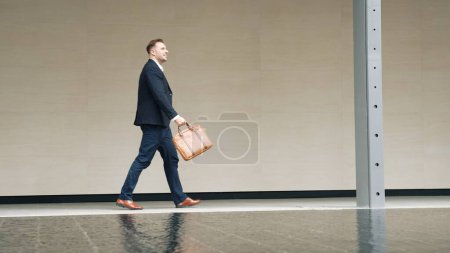 Photo for Side view of business people holding suitcase and walking to workplace along the street in urban city. Professional project manager going to meeting while wearing formal suit walk at outdoor. Urbane. - Royalty Free Image