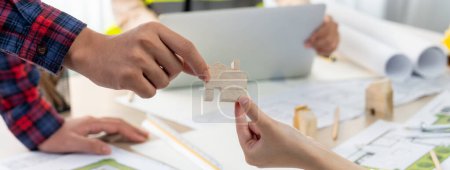 Professional engineer and architect collaborate on eco house project at meeting table with green design blueprint and architectural equipment at modern office. Focus on hand. Close up. Delineation.