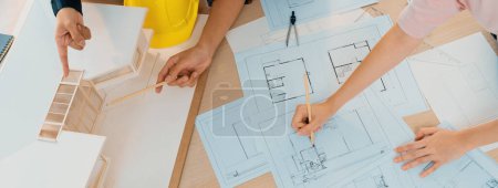 Photo for Skilled architect engineer team and interior designer meeting presents house construction on table with blueprint and architectural equipment.scatter around. Focus on hand. Top view. Burgeoning. - Royalty Free Image