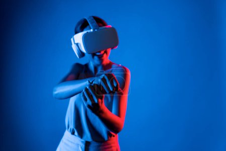 Photo for Smart female stand wear VR headset connecting metaverse, future cyberspace community technology. Elegant woman using hands controlling virtual laser saber seriously play fighting games. Hallucination. - Royalty Free Image