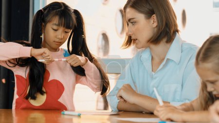 Photo for Panorama shot of happy diverse student and smart teacher drawing and coloring by using marker at drawing book. Multicultural learner using drawing book together at art lesson. Relaxation. Erudition. - Royalty Free Image