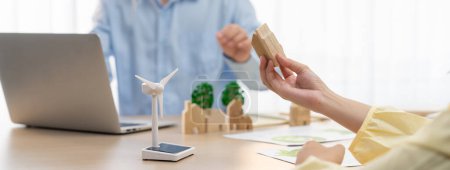 Photo for Businesswoman decides to Invest in green business. Skilled architects plan to build a eco house by using renewable energy at table with environmental document scatter around. Close up. Delineation. - Royalty Free Image