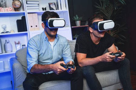 Photo for Buddy friend gamers playing video game using joysticks and VR headset of virtual technology in reality in studio room with neon blue light. Comfy living indoor with cheerful fighting winner. Sellable. - Royalty Free Image