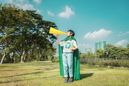 Téléchargez les photos : Jeune garçon super-héros avec symbole de recyclage et cape faire une annonce avec conférencier sur la sensibilisation à l'environnement pour la gestion du recyclage des déchets respectueux de l'environnement comme sa mission de sauver la Terre. Pneumatique - en image libre de droit