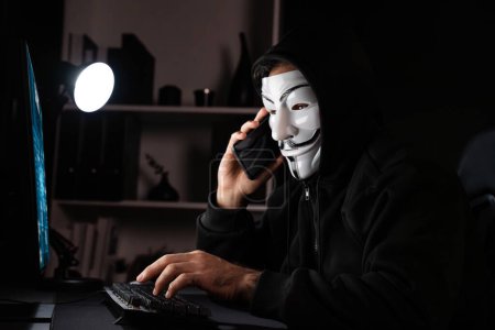 Foto de Blanco sonriente máscara anónima criminal llamando a la víctima, convencer a hackear la información personal, haciendo programa de cifrado de pantalla compartida por la aplicación hacker en el sistema de servidor de datos en la privacidad. Conjetura. - Imagen libre de derechos