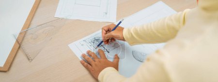 Photo for Cropped image of skilled architect designer hand draws blueprint with architectural equipment and blueprint. Creative working and design concept. Closeup. Focus on hand. Back view. Variegated. - Royalty Free Image