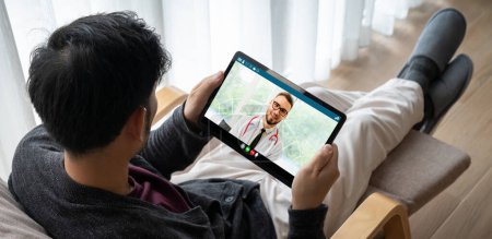 Téléchargez les photos : Médecin appel vidéo en ligne par l'application logicielle de télémédecine modish pour réunion virtuelle avec le patient - en image libre de droit