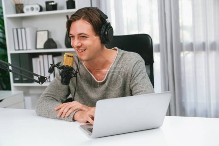 Photo for Host channel in smiling smart broadcaster recording, talking show with script and smartphone on desk on live social media, wearing headphones to record video streamer at modern home studio. Pecuniary. - Royalty Free Image