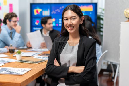 Foto de Retrato de la joven mujer de negocios asiática feliz o analista mirando a la cámara con su colega analizando el análisis de datos en la reunión de planificación de la estrategia empresarial dinámica de inversión. Habilimiento - Imagen libre de derechos