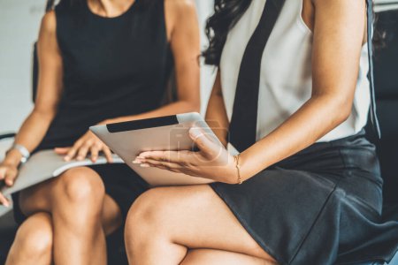 Téléchargez les photos : Deux femmes d'affaires discutent affaires tout en regardant les données financières dans leurs mains. Ils sont assis sur les chaises dans la salle de réunion du bureau. uds - en image libre de droit