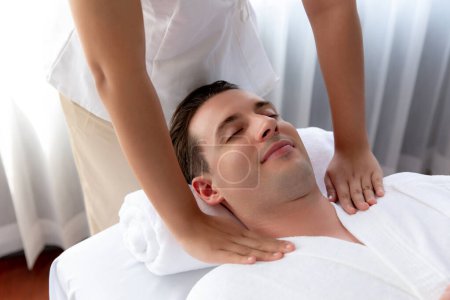 Téléchargez les photos : Homme caucasien client appréciant relaxant massage spa anti-stress et dorloter avec beauté loisirs de la peau dans la lumière du jour salon de spa d'ambiance dans un complexe de luxe ou un hôtel. Tranquillité - en image libre de droit