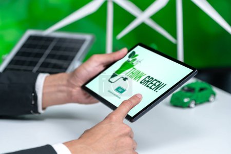 Téléchargez les photos : Homme d'affaires travaillant dans le bureau développant un plan ou un projet sur l'énergie alternative écologique avec affichage de la technologie des cellules solaires sur l'écran de la tablette pour un environnement plus vert dans le cadre de l'effort de RSE. Pneumatique - en image libre de droit