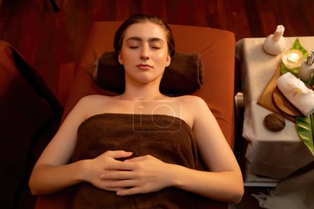 Photo for Top view woman customer enjoying relaxing anti-stress spa massage and pampering with beauty skin recreation leisure in warm candle lighting ambient salon spa at luxury resort or hotel. Quiescent - Royalty Free Image