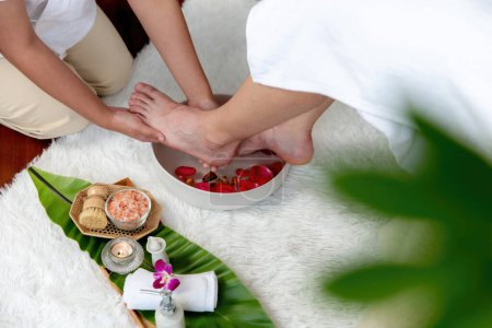 Man indulges in blissful foot massage at luxurious spa salon while masseur give reflexology therapy in gentle day light ambiance resort or hotel foot spa. Quiescent