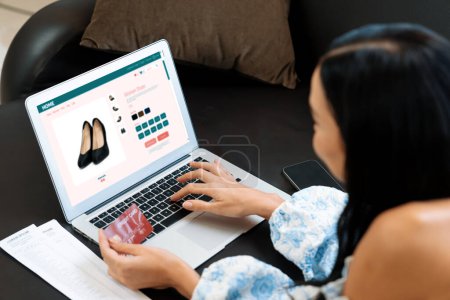 Photo for Young woman using laptop with credit card for internet banking, online shopping E commerce by online payment gateway at home. Modern and convenience online shopping with debit card. Blithe - Royalty Free Image