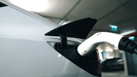 Closeup EV voiture électrique branchée à la station de charge, recharger la batterie au centre commercial parking au centre-ville urbain avec un style de vie vert propre énergie durable des entrailles de véhicules électriques