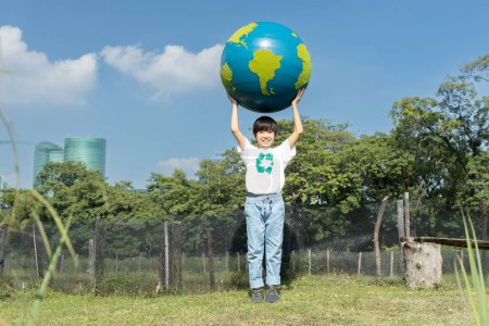 Photo for Young asian boy holding big planet Earth globe at natural park with sky background as Earth day to save this planet with ESG principle and environment friendly energy for brighter future. Gyre - Royalty Free Image