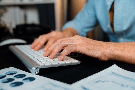 Photo for Cropped image of sales manager typing with keyboard with business paragraph dynamic data marketing analysis plan surrounded paper sheet and pc monitor report at home office at night. Pecuniary. - Royalty Free Image