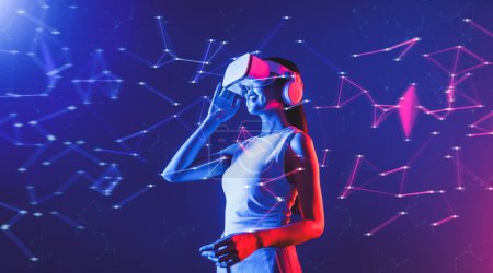 Photo for Female stand in cyberpunk neon light wear white VR headset and tank top connecting metaverse, future cyberspace community technology, She look in virtual reality object holding goggles. Hallucination. - Royalty Free Image
