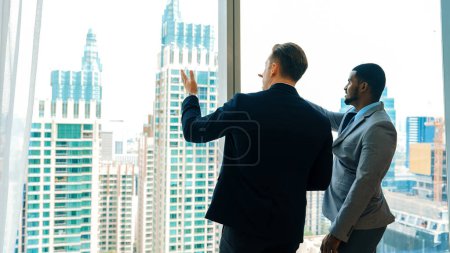 Photo for Back view diverse team of ambitious business people standing in ornamented office gazing out window to cityscape skyline. Determination and business ambition drive their career toward to bright future - Royalty Free Image