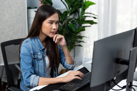 Photo for Working young beautiful asian creative manager typing keyboard to search on pc with website design on social media channel online planning with blue jeans shirt at modern home office. Stratagem. - Royalty Free Image