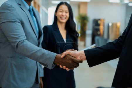 Photo for Closeup of business hands shaking between businessman and professional male leader while smart businesswoman stand near at modern office corridor. Represented unity, corporate, teamwork. Ornamented. - Royalty Free Image