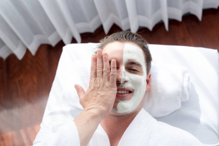 Photo for Serene ambiance of spa salon, man customer indulges in rejuvenating with luxurious face cream massage with modern daylight. Facial skin treatment and beauty care concept. Quiescent - Royalty Free Image