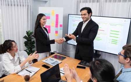 Proud boss or entrepreneur give credit and praise his employee with handshake after made successful sales or marketing plan to encourage and motivate group of diverse ethnic office workers. Habiliment