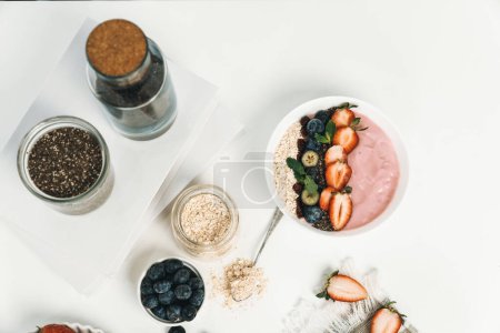 Photo for Presented by fruits putting yogurt toppings with strawberry, berry, oats, raisins and chia seed decorated by peppermint in white blow. Pink background. Set of healthy dairy product choice. Pecuniary. - Royalty Free Image