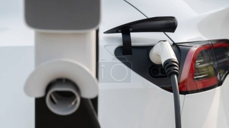 Téléchargez les photos : Closeup EV batterie de recharge de voiture électrique au parking dans la zone commerciale de la ville ou un centre commercial. Technologie d'énergie alternative pour véhicule rechargeable pour un voyage durable et respectueux de l'environnement. Expedient - en image libre de droit