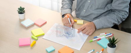 Photo for Skilled businessman brainstorms marketing ideas using mind maps. Successful male startup leader drafts financial plan on table with sticky notes scatter around. Closeup. Focus on hand.Variegated. - Royalty Free Image