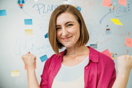 Portrait of young beautiful caucasian businesswoman smiling and posing with confident while looking at camera in front of whiteboard with mind map and colorful sticky notes. Closeup. Immaculate.