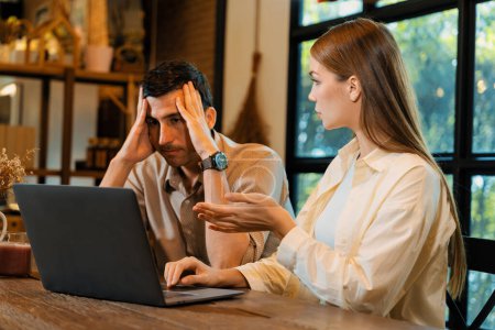 Young couple working remotely on laptop in cafe look tired and frustrated. Digital nomad freelancers or college students struggling to meet a deadline overwhelmed by workload. Expedient