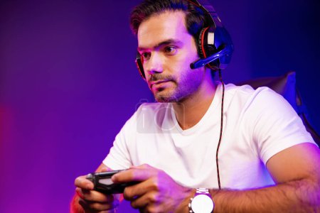 Photo for Smart gaming streamer talking with team member players with joystick to control game, mic for communicate with others on streaming live on social media at digital neon lighting studio room. Surmise. - Royalty Free Image