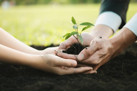 Homme d'affaires cultiver et cultiver des plantes sur un sol fertilisé avec le jeune garçon comme éco-entreprise engagée à la responsabilité sociale des entreprises, réduire les émissions de CO2 et adopter le principe ESG pour un avenir durable.