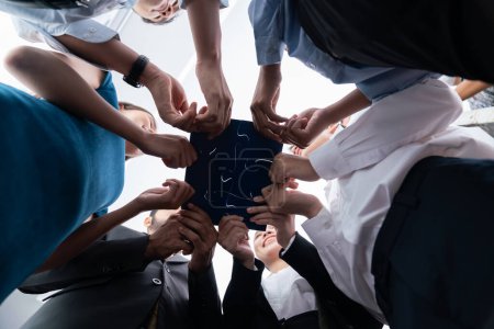 Photo for Below view of diverse corporate officer workers collaborate in office connecting puzzle pieces as partnership and teamwork concept. Unity and synergy in business idea by merging jigsaw puzzle. Concord - Royalty Free Image