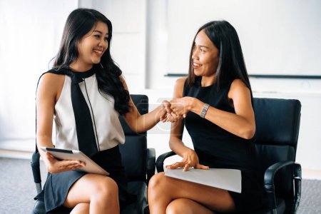Photo for Two young Asian businesswomen do handshake in office. Business friends and community concept. uds - Royalty Free Image