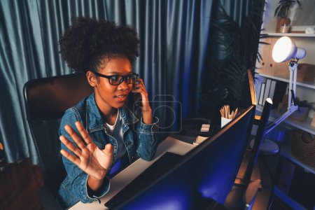 Téléchargez les photos : Jeune femme d'affaires afro-américaine portant une chemise en jeans se concentrant sur le travail du projet sur écran d'ordinateur portable, portant une chemise en jeans. Concept de devise d'investissement ou blogueur d'actifs. Tastemaker. - en image libre de droit