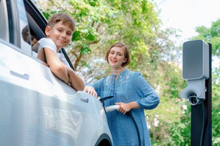 Photo for Family road trip vacation with electric vehicle, mother and son recharge EV car with green and clean energy. Nature and travel with eco-friendly car for sustainable environment. Perpetual - Royalty Free Image