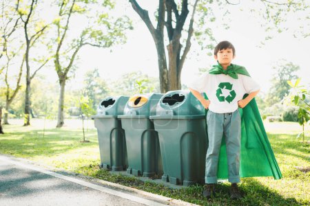 Téléchargez les photos : Joyeux jeune garçon super-héros avec cape et symbole de recyclage promouvoir le recyclage des déchets, réduire et réutiliser les encouragements comme phare de la sensibilisation éco durable pour les générations futures. Pneumatique - en image libre de droit