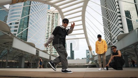 Photo for Group of professional street dancer cheer up while asian hipster perform freestyle footstep at city surrounded by people with low angle camera. Break dance concept. Outdoor sport 2024. Sprightly. - Royalty Free Image