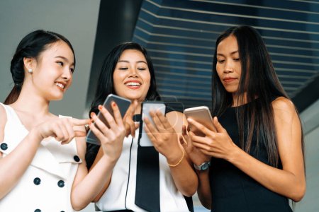Foto de Tres amigas conversando mientras miran el teléfono móvil en sus manos. Concepto de medios sociales, noticias de chismes y compras en línea. BARROS - Imagen libre de derechos